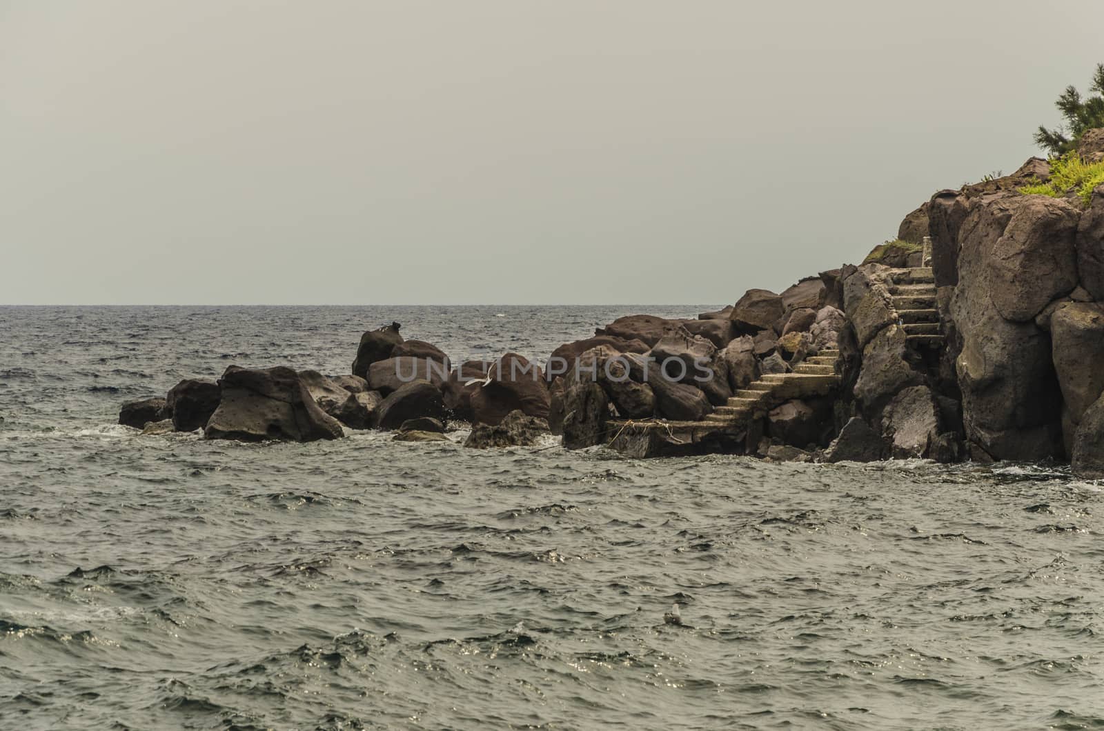 Coast of rocks between which you see the stairs to a small pier on the island of panarea on the Tyrrhenian Sea