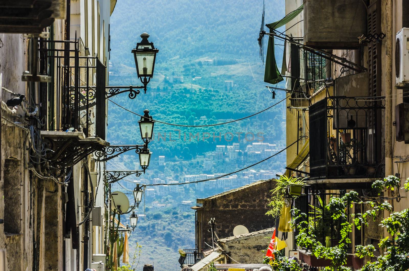 Steep street with lampposts and old constructions with their balconies in the city of monreale near palermo sicily