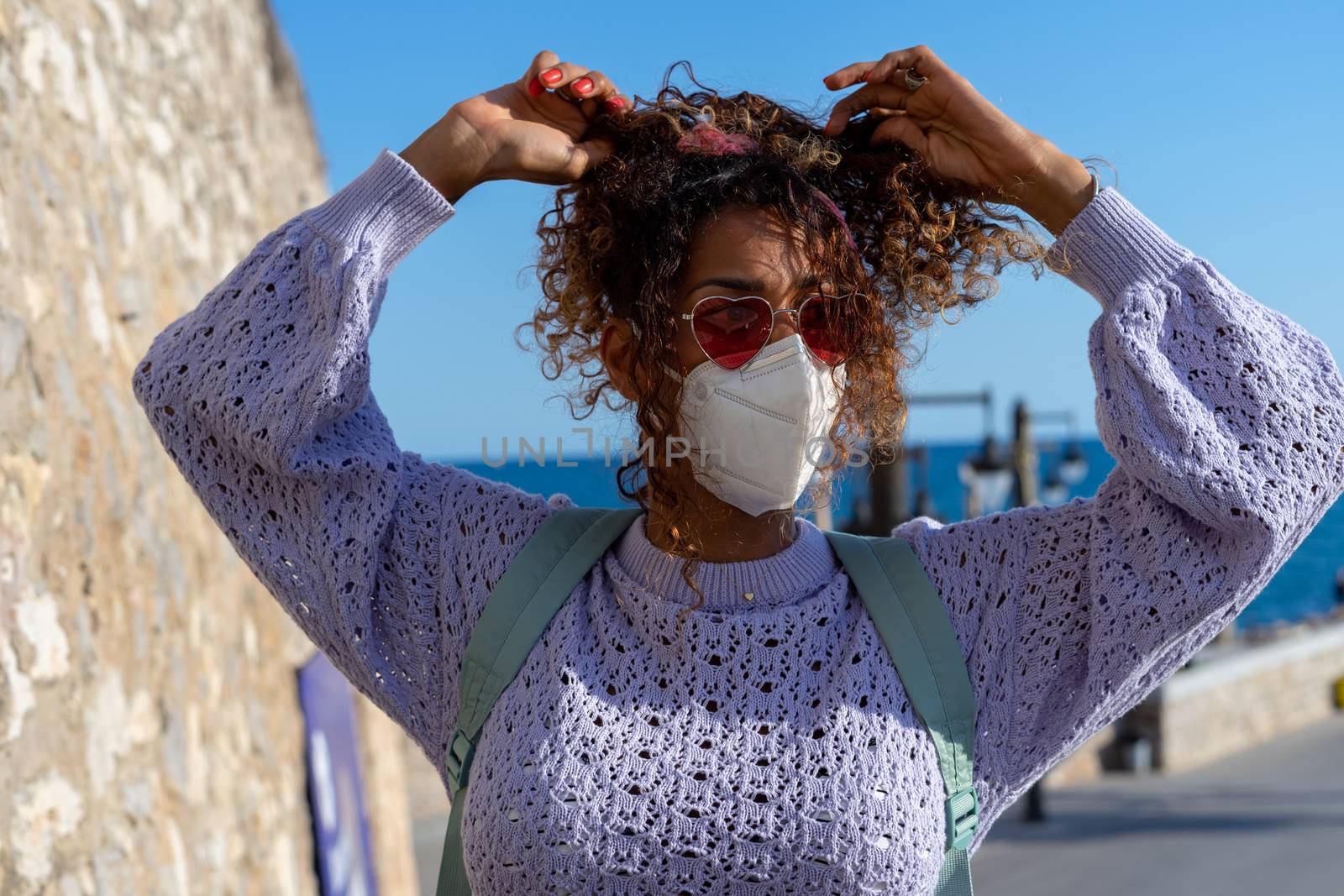 Portrait of an attractive young black woman walking with backpack and mask. Sightseeing