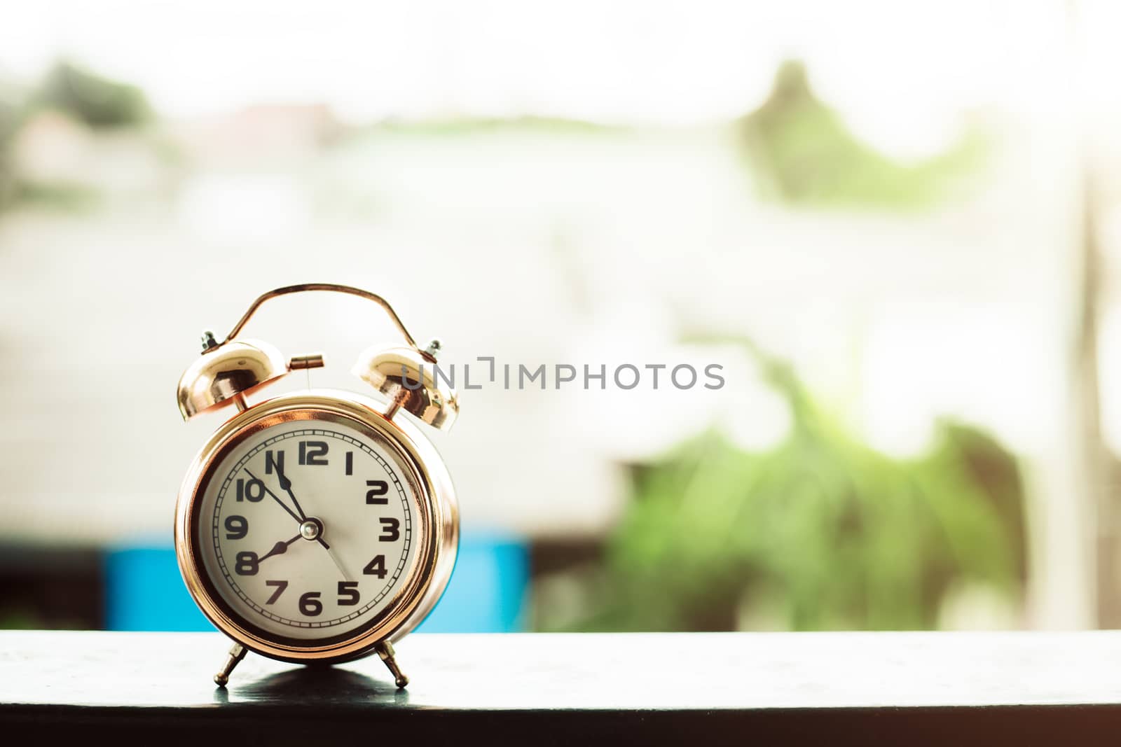 Bell alarm clock against blurred outdoor background with copy space for time management concept