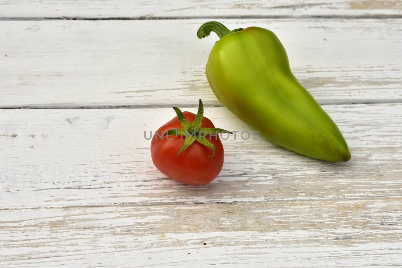 red tomato and green bell pepper pod on a wooden vintage table