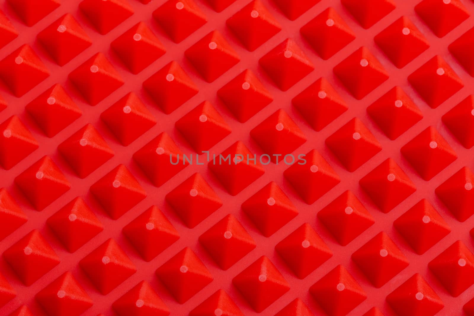 abstract red silicone pyramids array close-up background.
