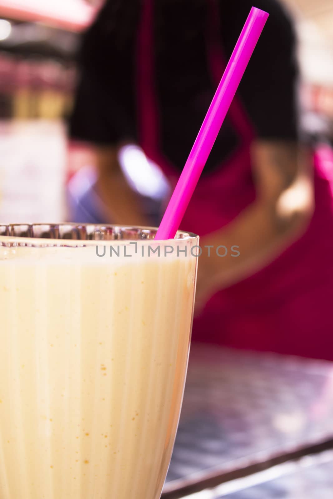 Glass bowl with fruit smoothie and drinking straw