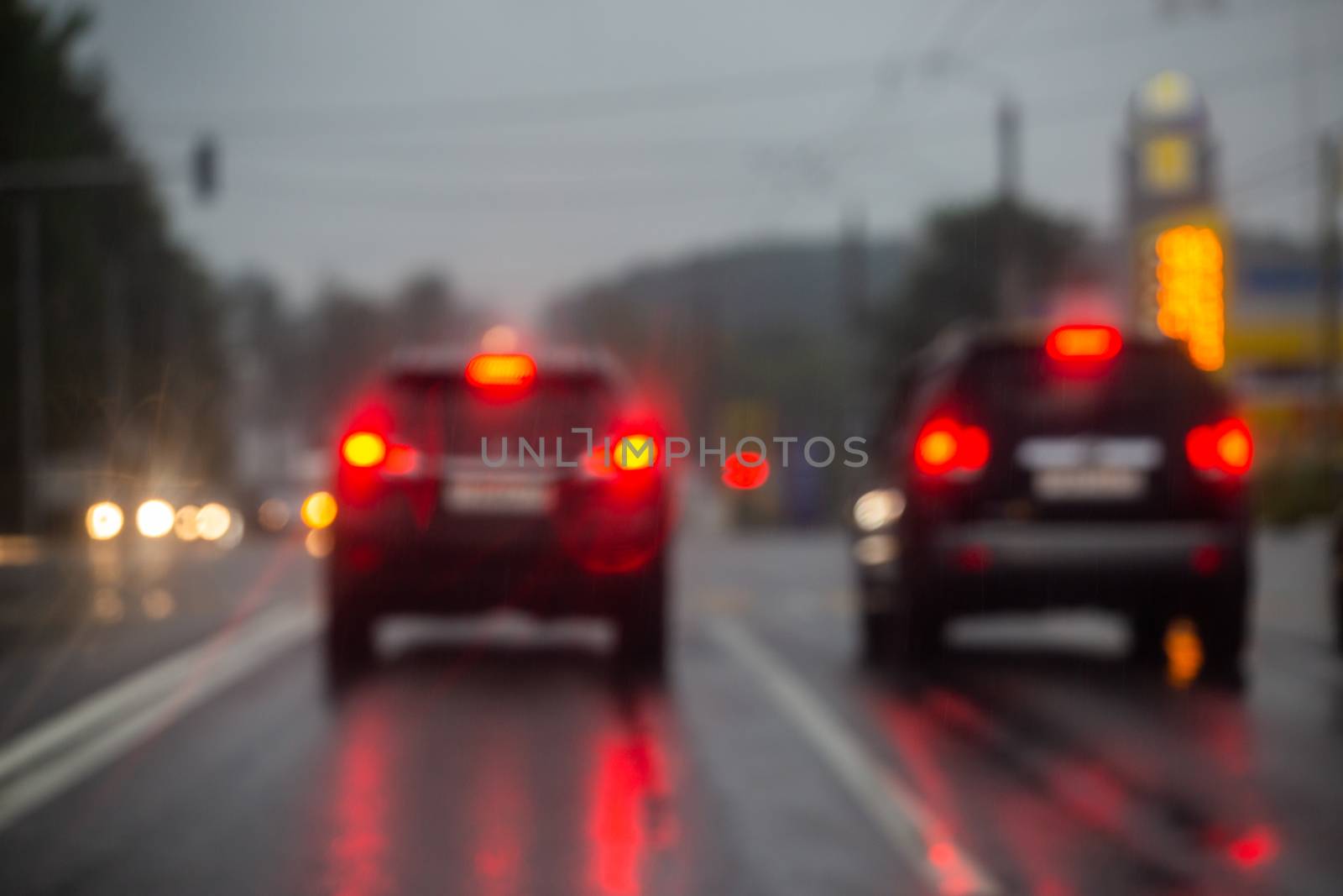 Defocused picture of evening city street car traffic after rain - view from road.