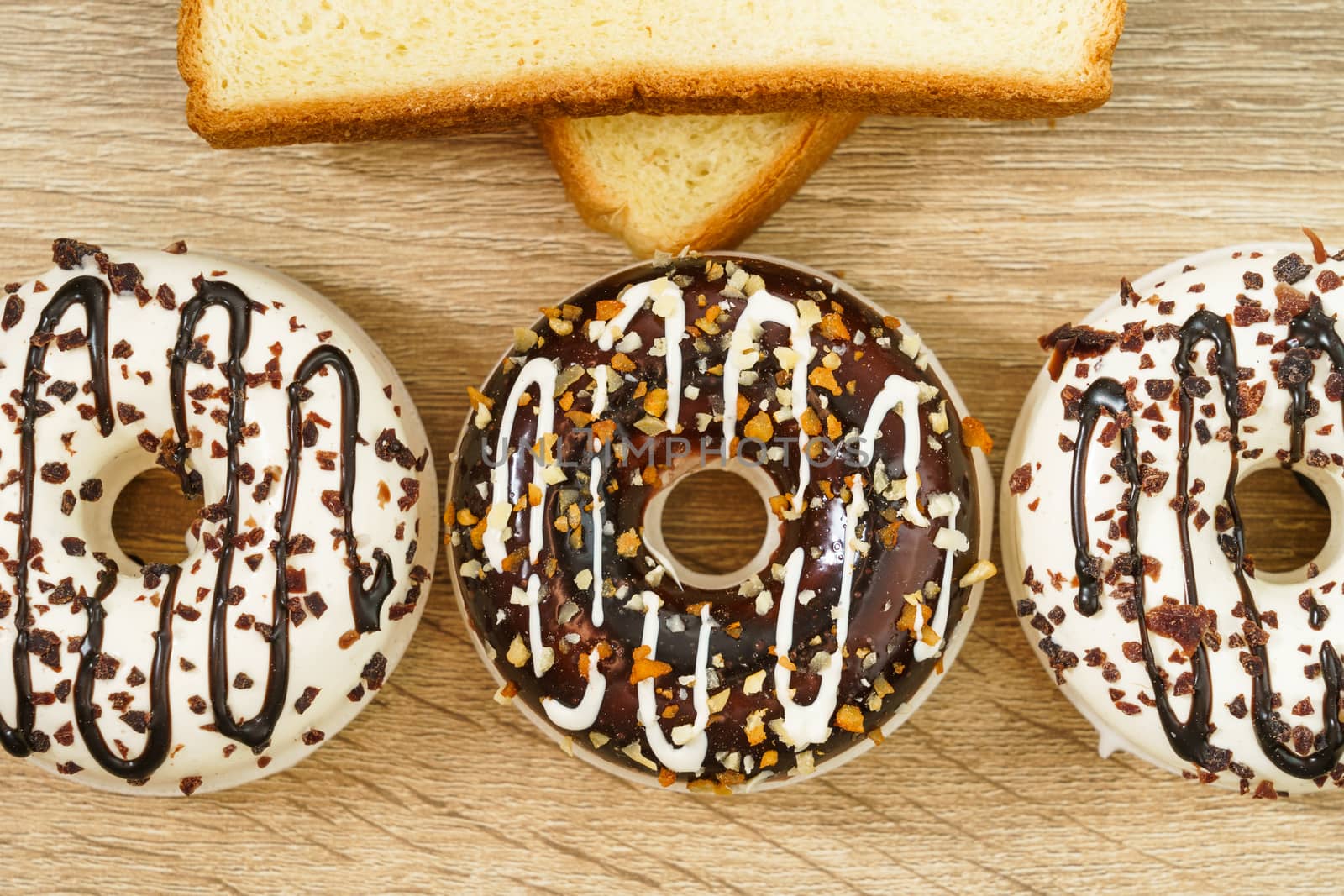 Round donuts and slice of bread on wood background by stoonn