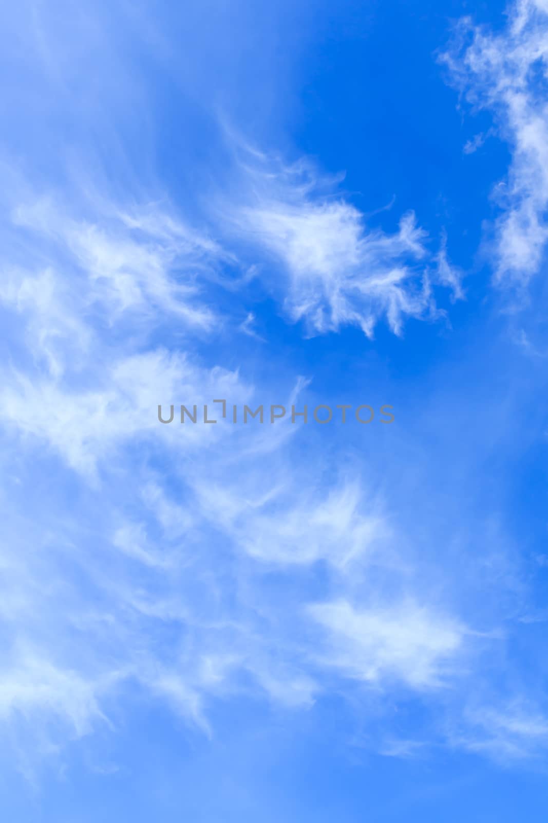 Vertical photo of Blue sky with delicate arabesques of light white cirrus clouds