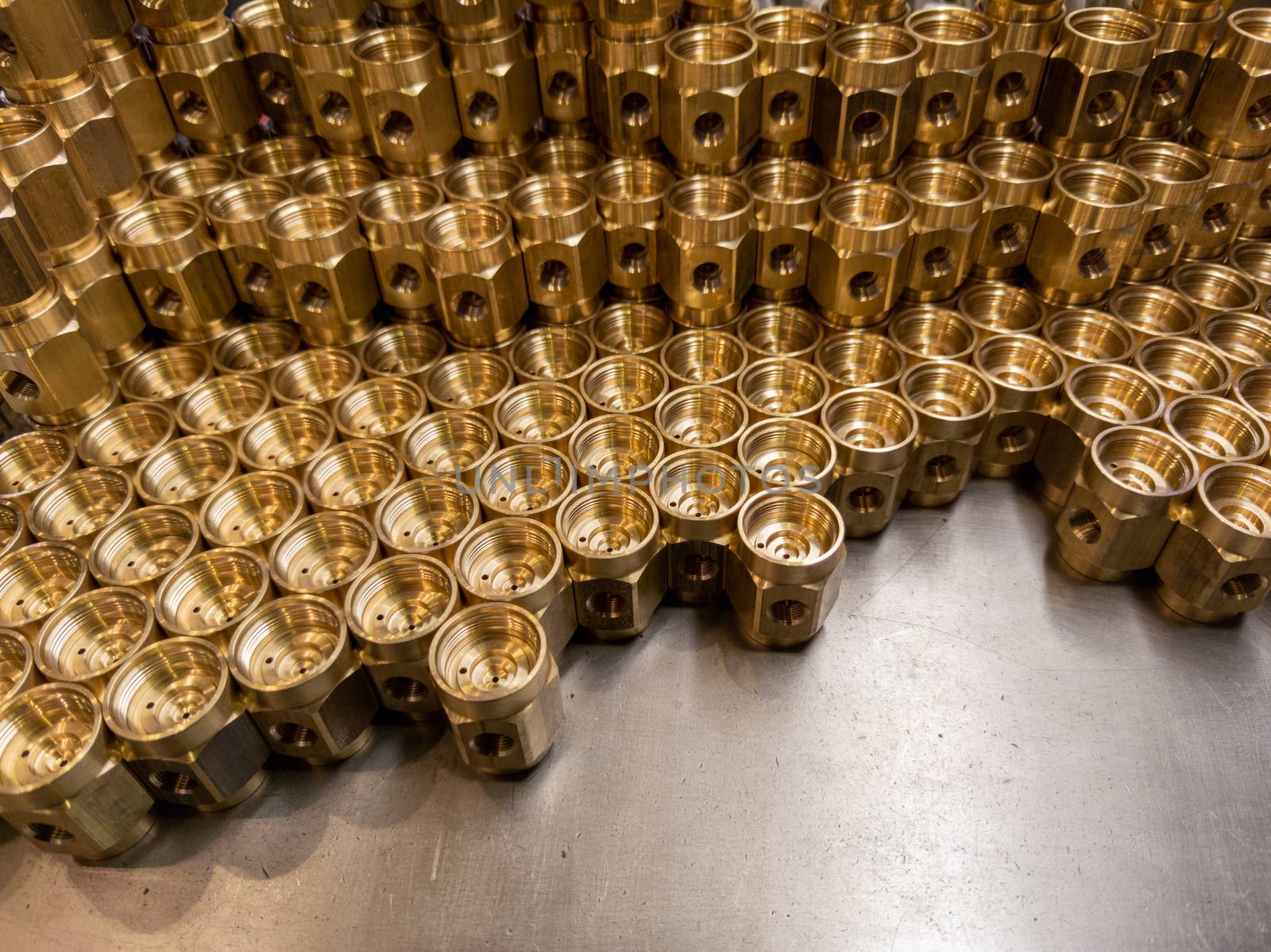 Shiny yellow metal parts background. An abstract industrial close-up background of shiny brass metal threaded hexagonal parts after turning and machining.