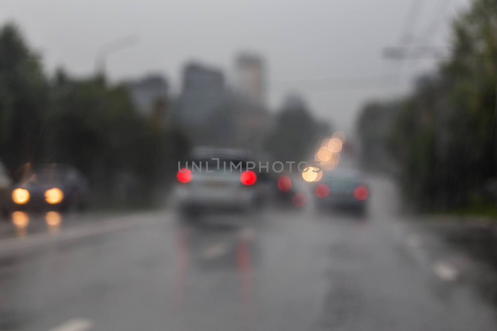 Defocused picture of evening city street car traffic after rain - view from road.