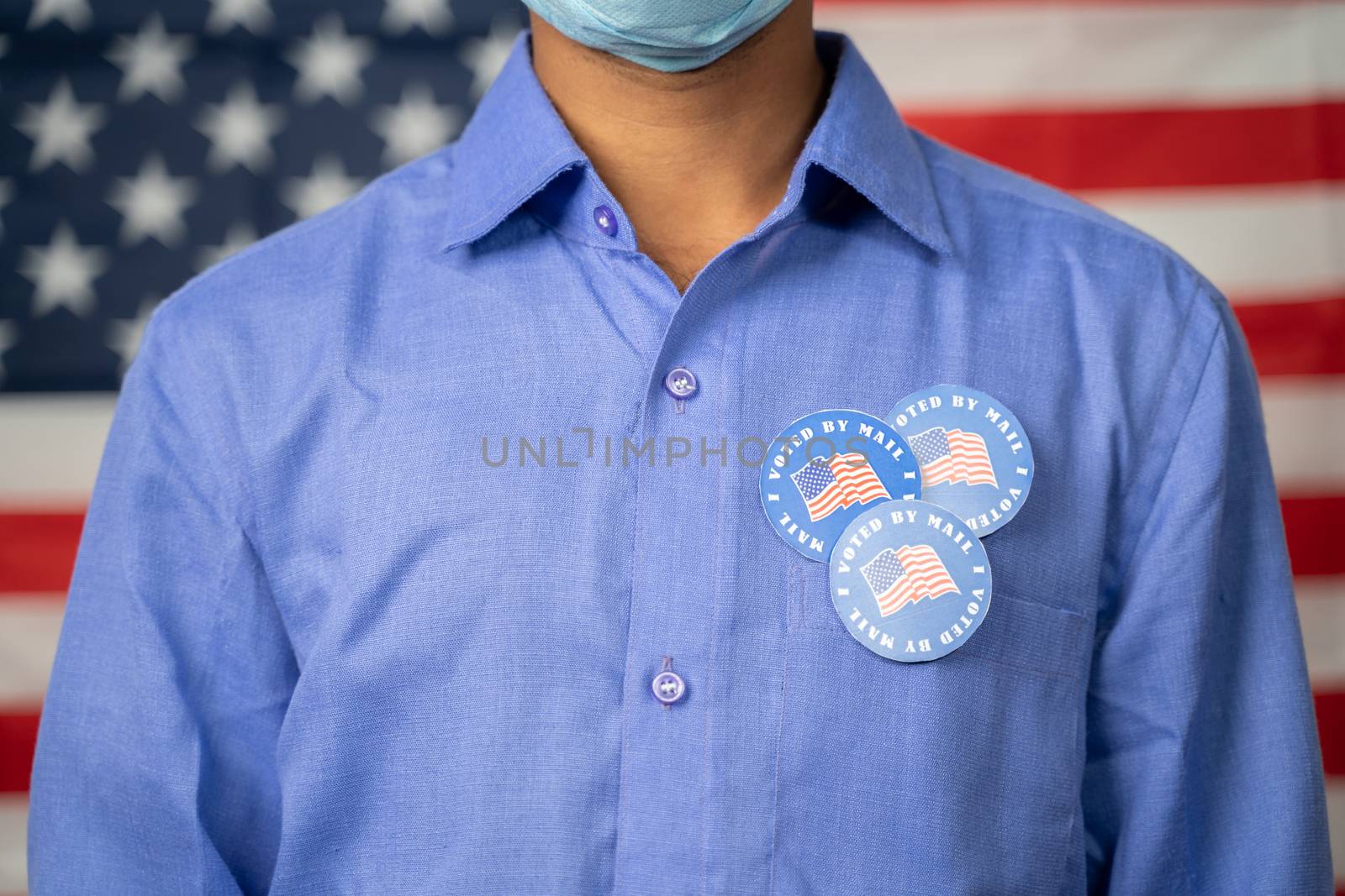 Unrecognizable Man with multiple I voted by mail sticker on his sticker with US flag as background - Concept of fraud in US election mail-in voting or vote by mail.