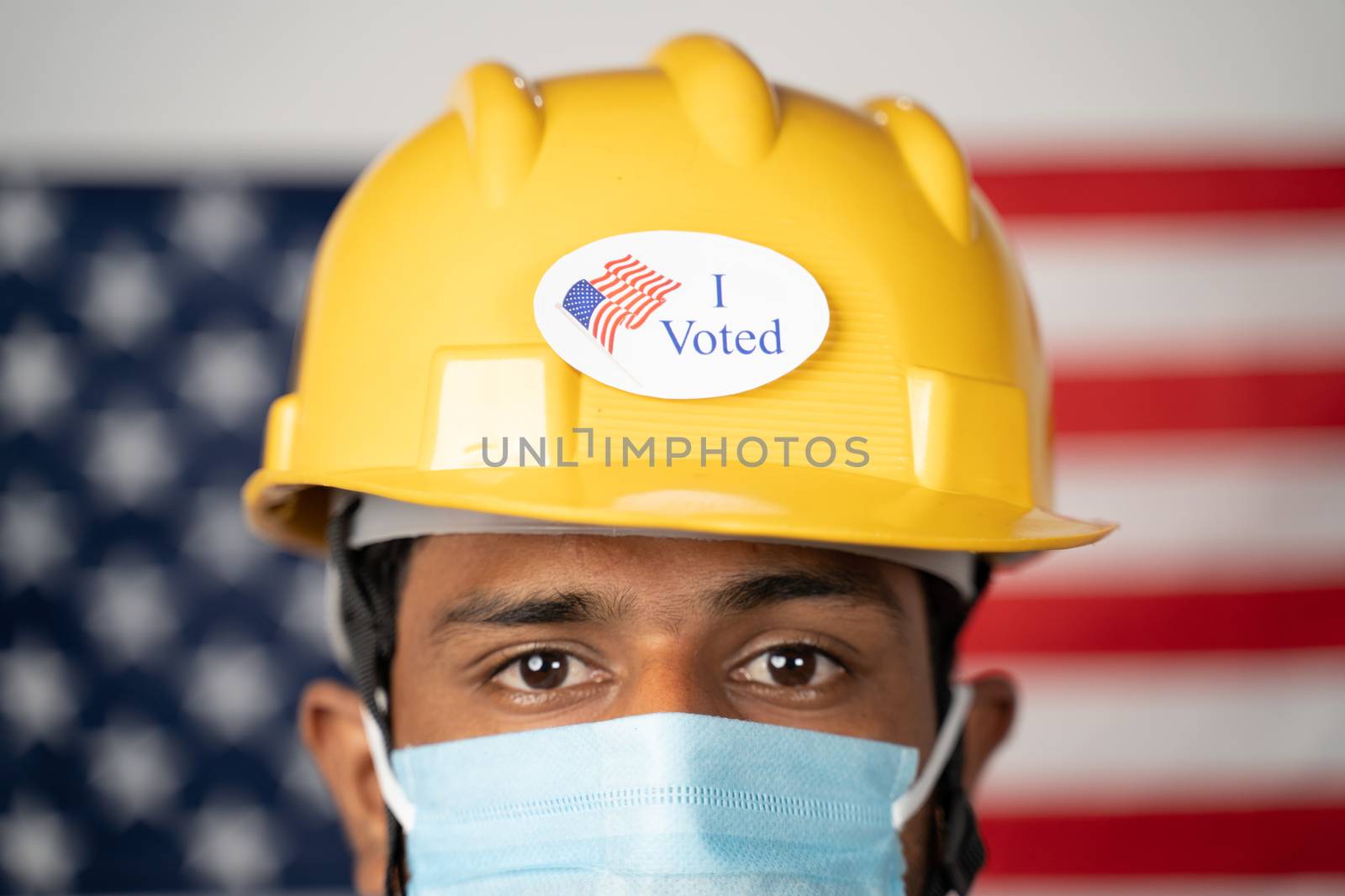 Close up of I voted sticker on worker hardhat with US flag as background - Concept of USA elections and voting