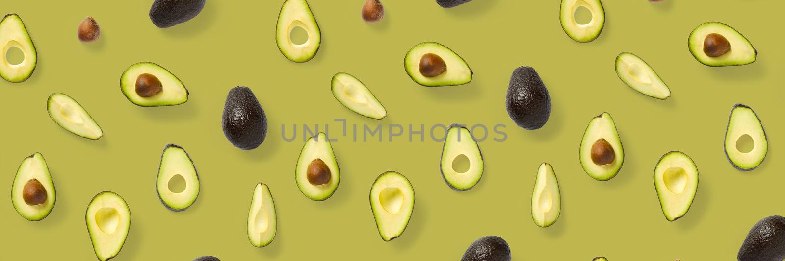 Avocado banner. Background made from isolated Avocado pieces on olive color background. Flat lay of fresh ripe avocados and avacado pieces. by PhotoTime