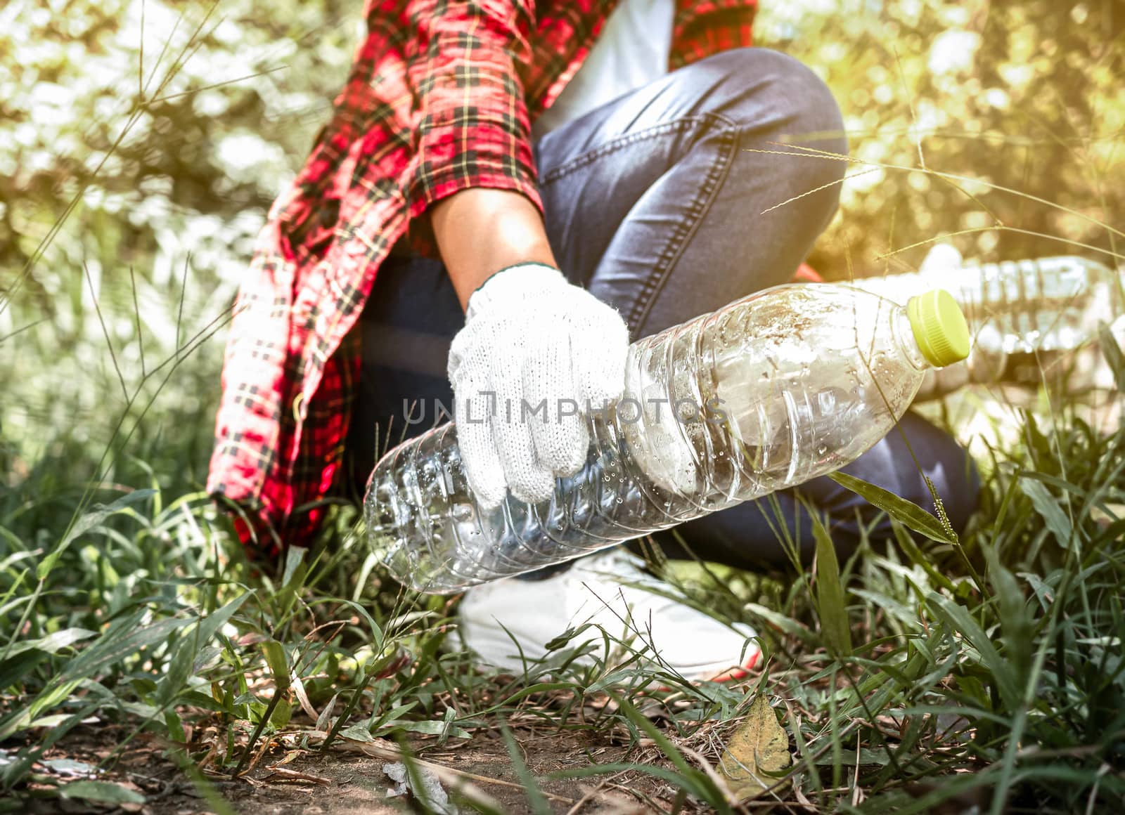 Close up of volunteers sit and picking up garbage in the park. E by TEERASAK