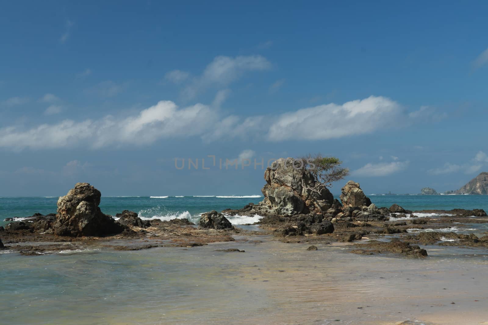 An idyllic beach in Lombok, Indonesia. The Mandalika beach is stony, with many rock formations emerging from the water. Rock formations on beach Kuta beach. Perfect day for relaxation.