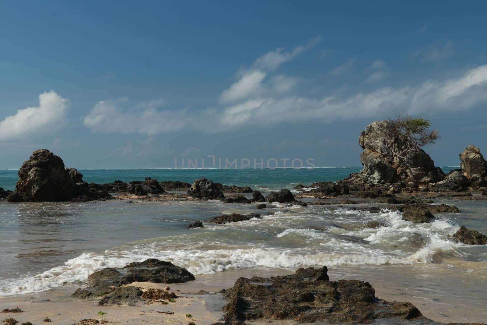 An idyllic beach in Lombok, Indonesia. The Mandalika beach is stony, with many rock formations emerging from the water. Rock formations on beach Kuta beach. Perfect day for relaxation.