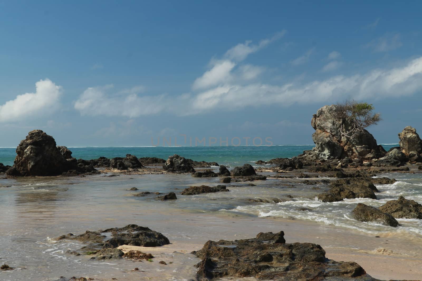 An idyllic beach in Lombok, Indonesia. The Mandalika beach is stony, with many rock formations emerging from the water. Rock formations on beach Kuta beach. Perfect day for relaxation.