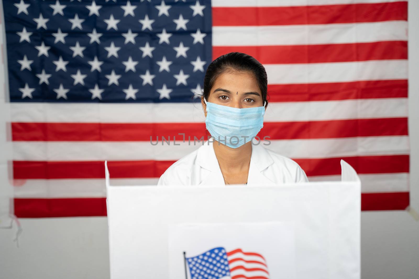 Doctor or nurse coming to polling booth with medical mask wearing for voting - concept of US election, in person voting showing with US flag as background