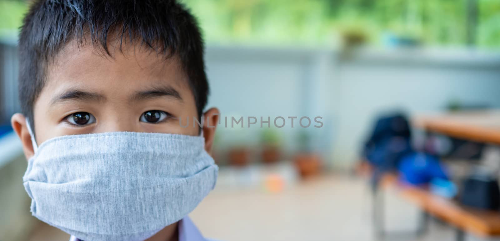 Close-up portrait of a cute boy wearing a protective mask and he is looking at the camera.