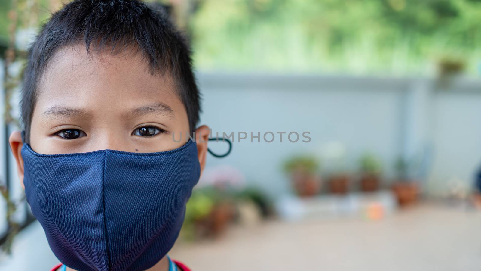 Close-up portrait of a cute boy wearing a protective mask and he is looking at the camera.