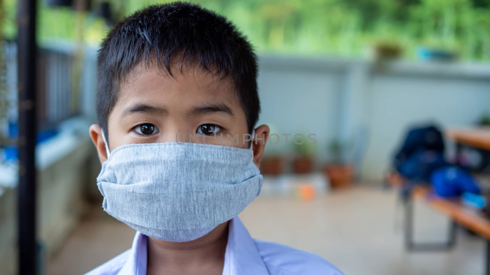 Close-up portrait of a cute boy wearing a protective mask and he is looking at the camera.