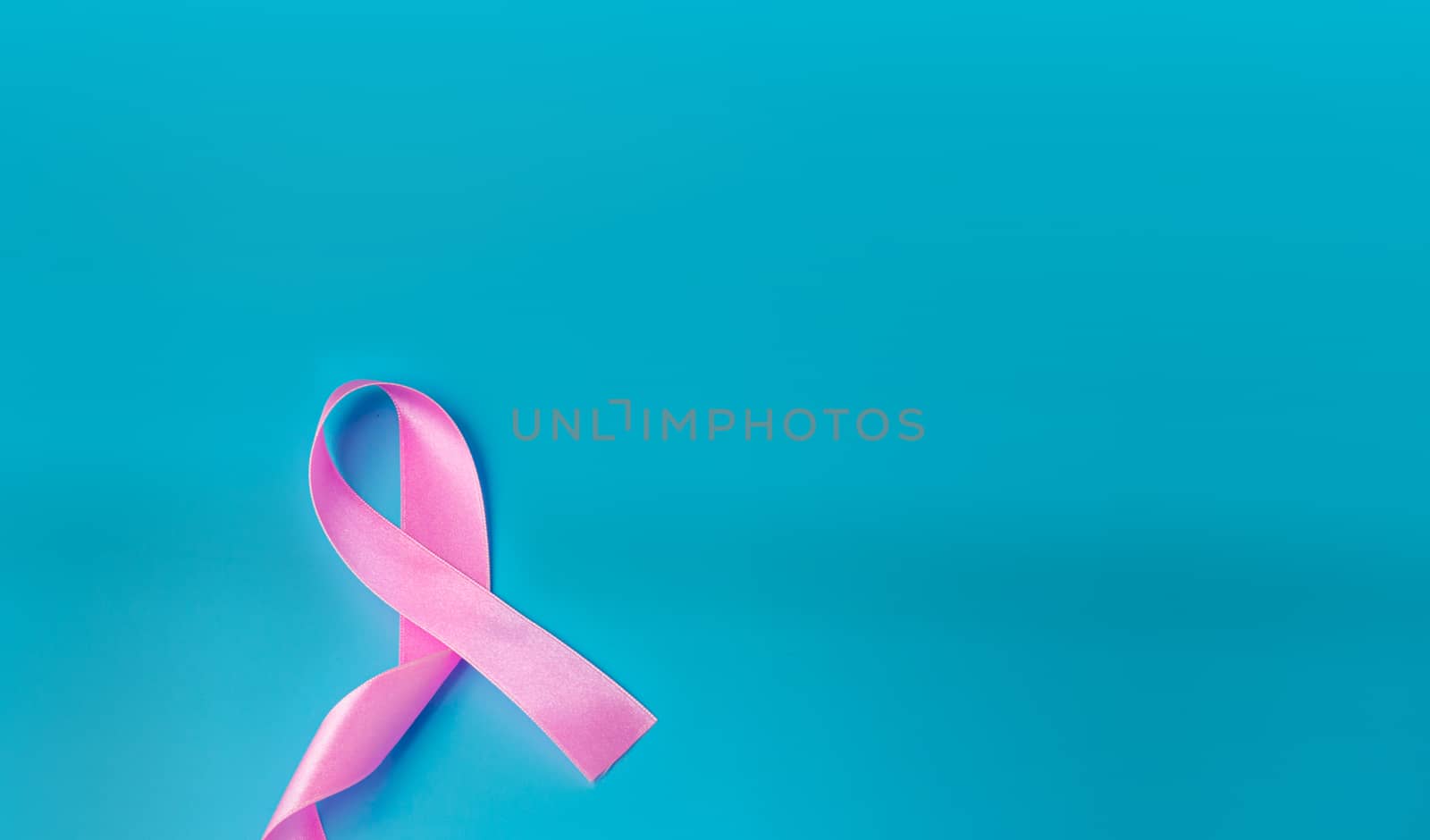 Pink ribbon On a blue background Conveys the awareness of cancer by Unimages2527