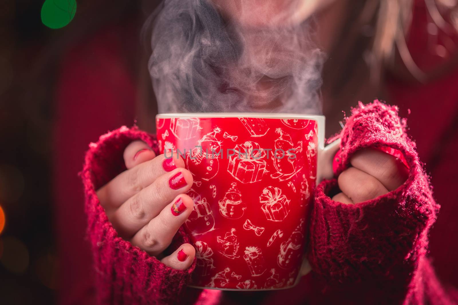 Detail of woman hands holding warm a cup of tea with steam. Blur Christmas background. Christmas or winter concept. by petrsvoboda91