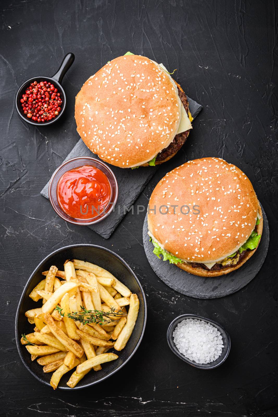 Beef burger and french fries on black background, top view.