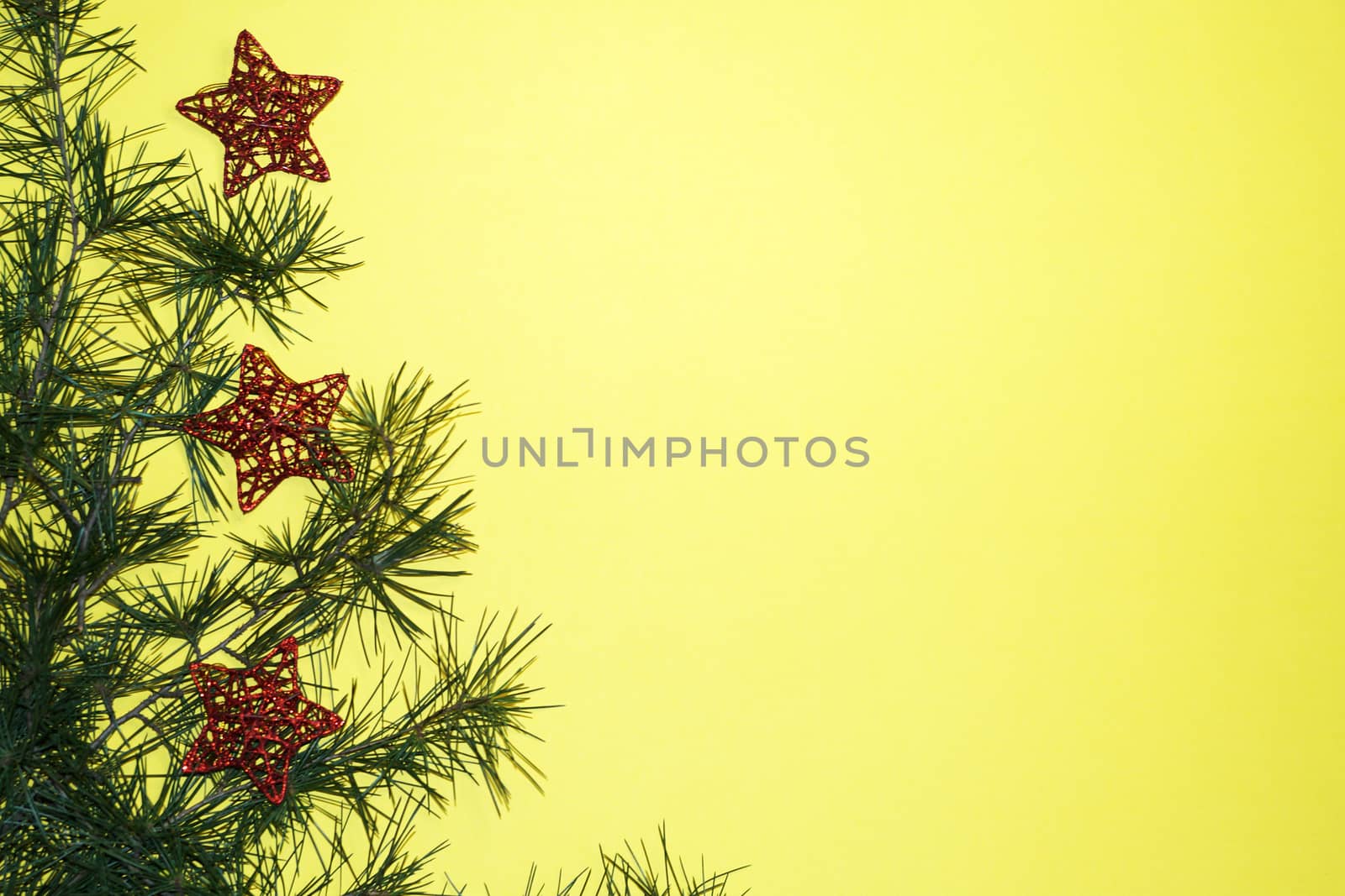 coniferous branches and Christmas tree decorations on a New Year's yellow background, copy space.