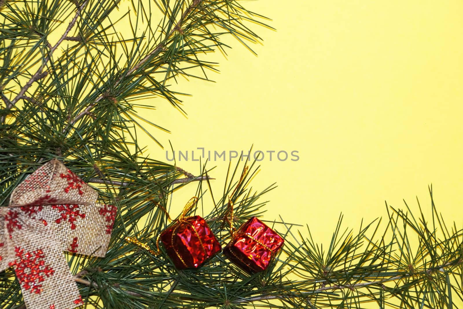 coniferous branches and Christmas tree decorations on a New Year's yellow background, copy space.