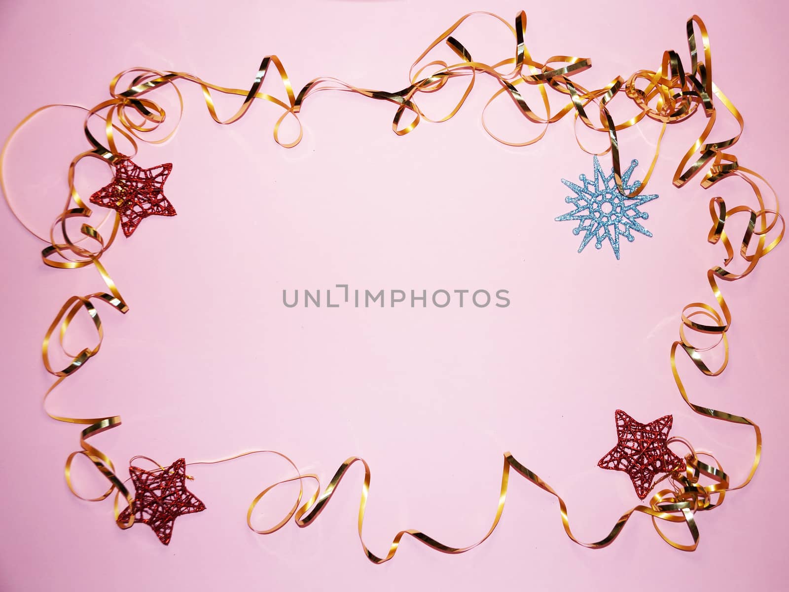 wavy frame made of gold ribbon with stars and snowflake on pink background, copy space for new year, christmas.