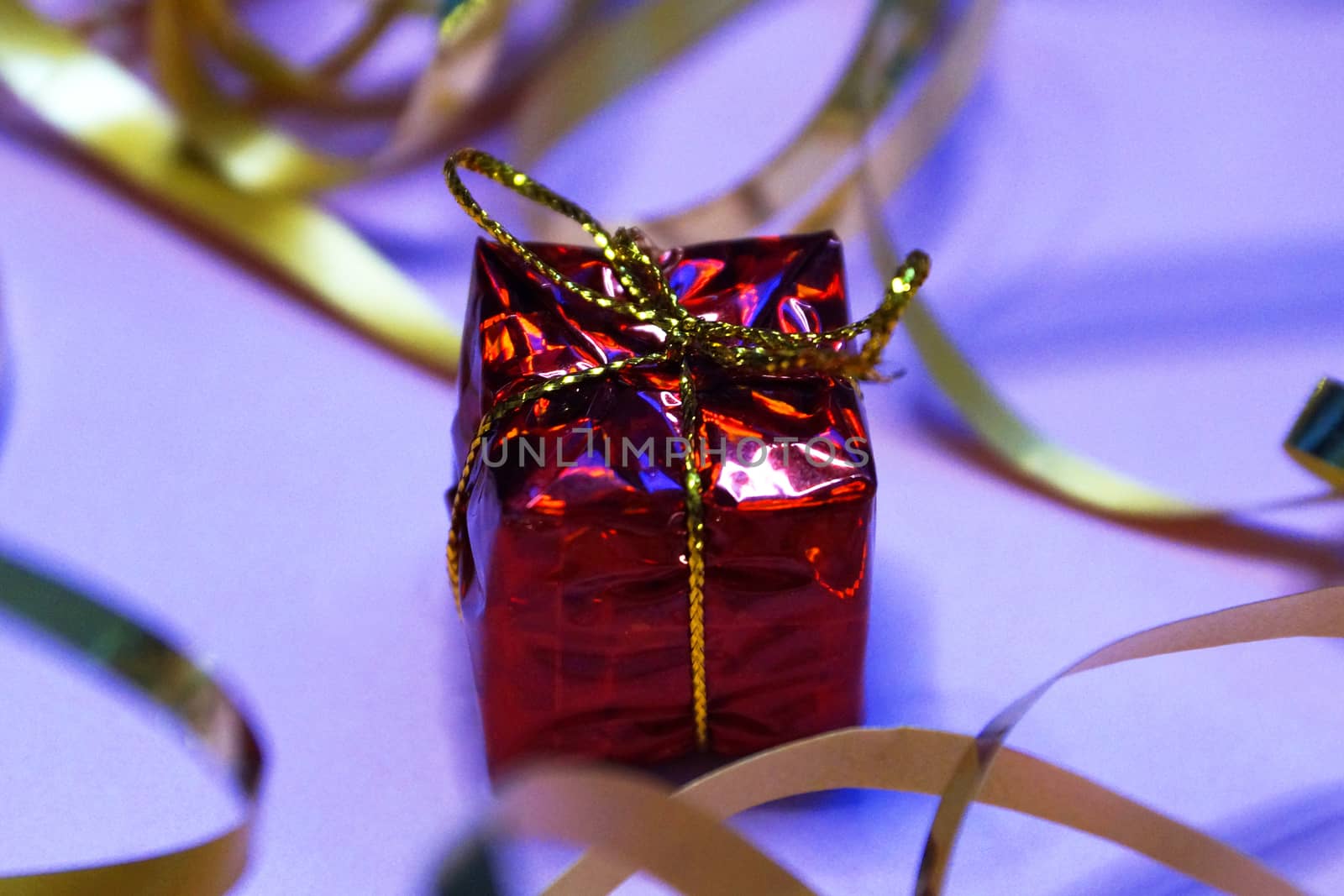 shiny red gift box and gold ribbon on pink background close up