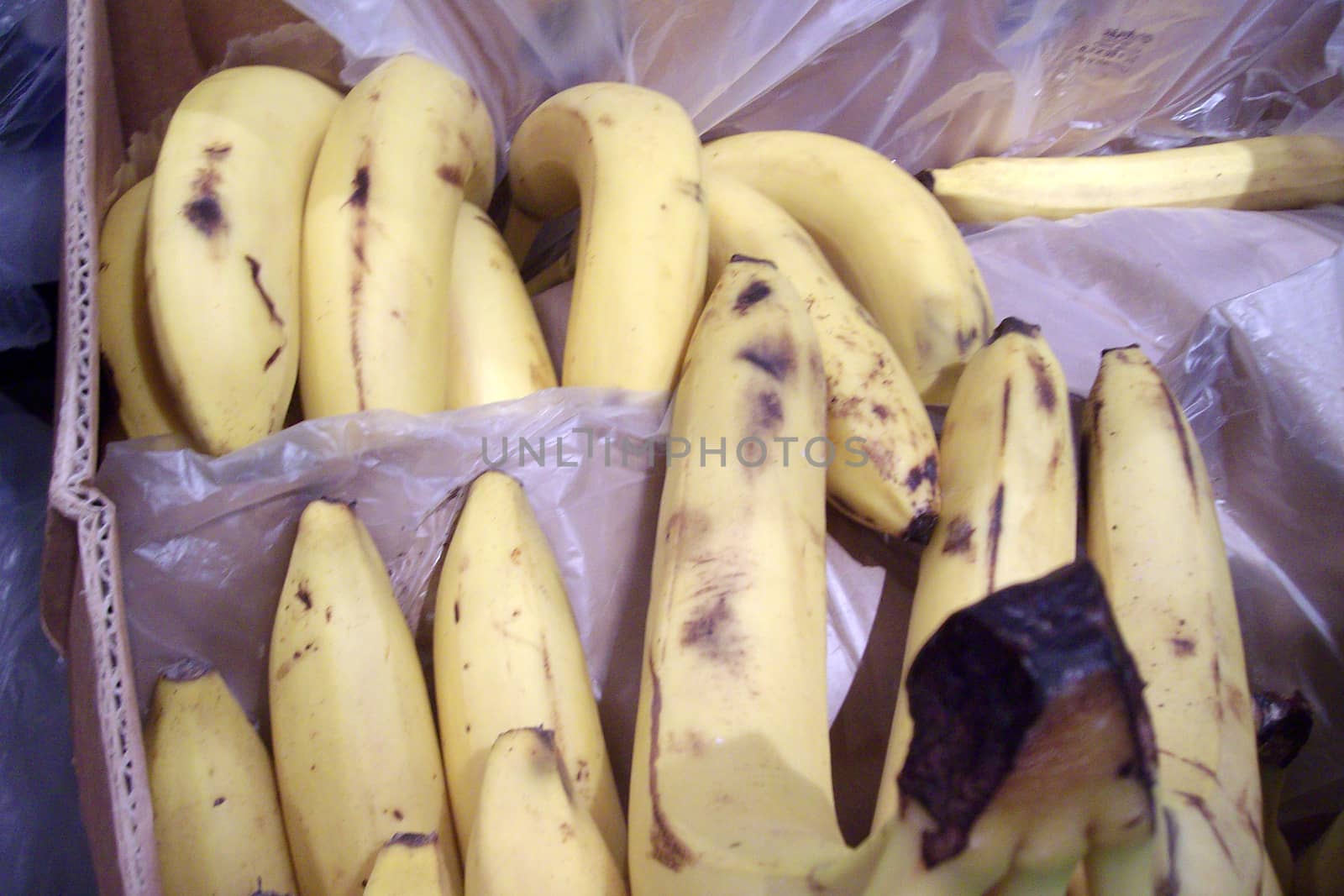 spoiled bananas with spots in a box in a store by Annado