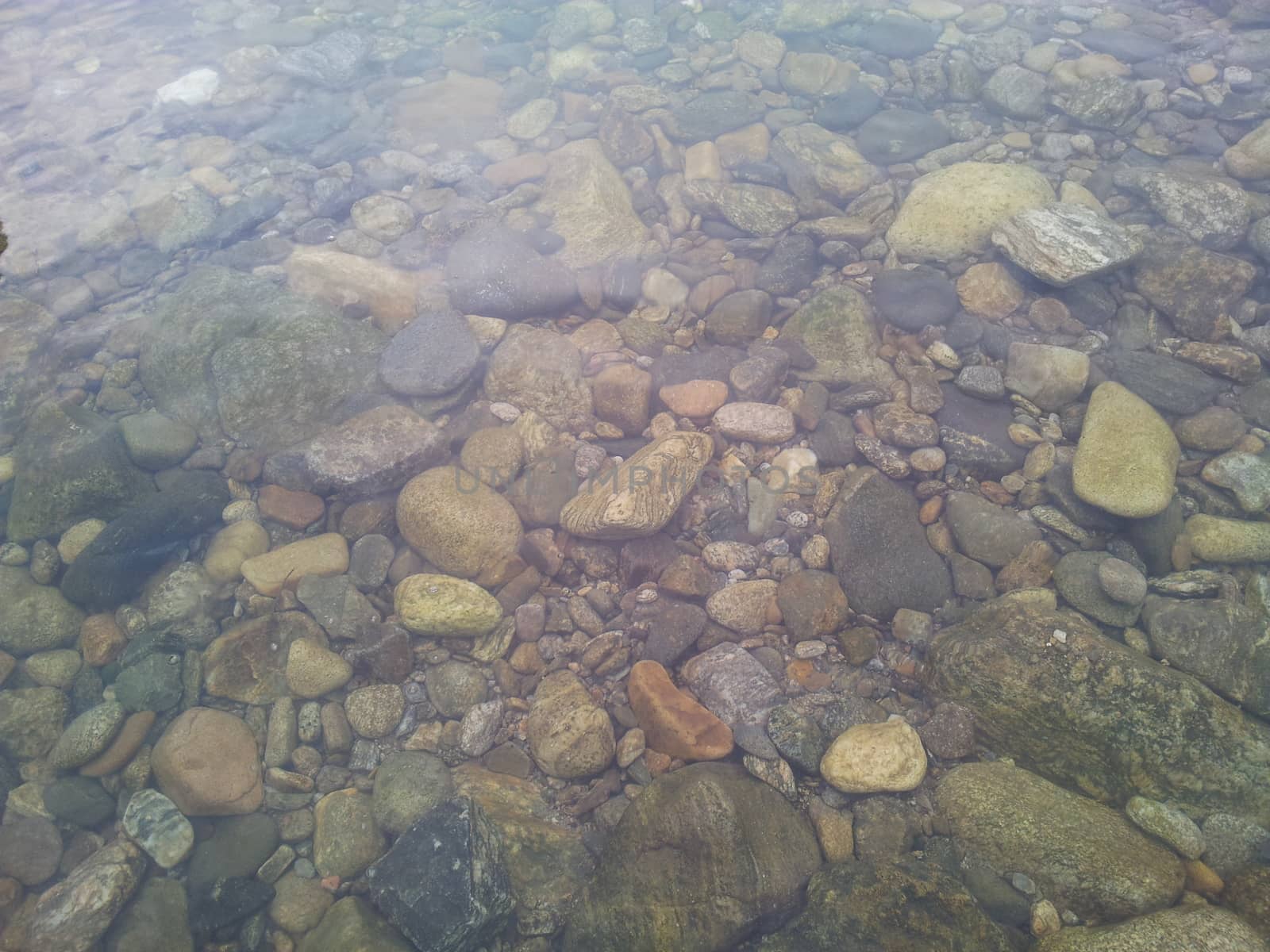 Transparent water surface with copy space for background and texture. Transparent water texture with view of stones under water.