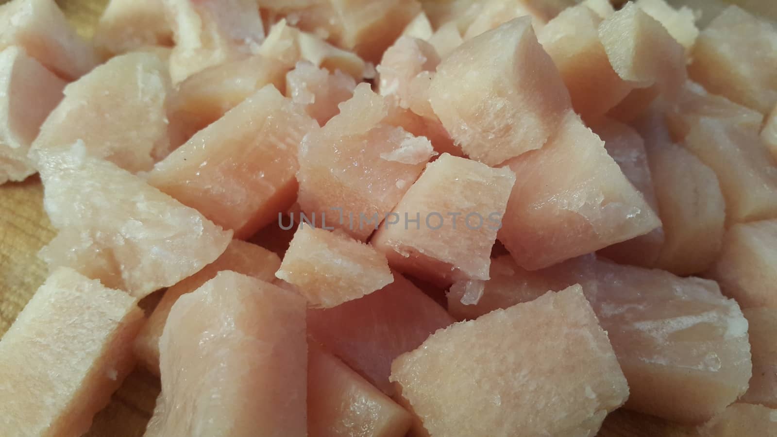 Close up top view of fresh finely chopped chicken meat cubes. White meat small steaks with meat fat.