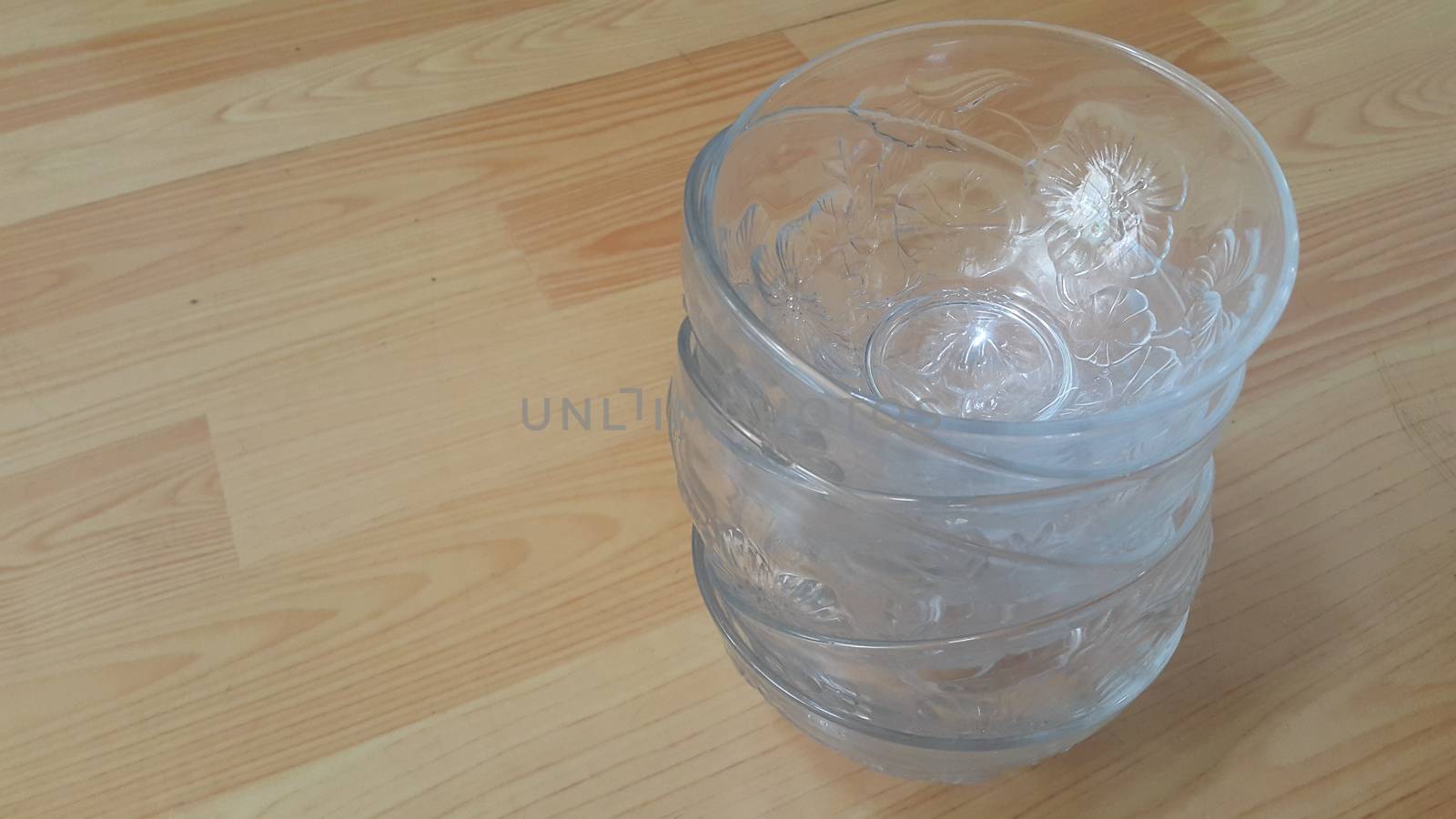 Top view of empty white glass bowls on a wooden floor. Glass bowl with flowers made on its wall