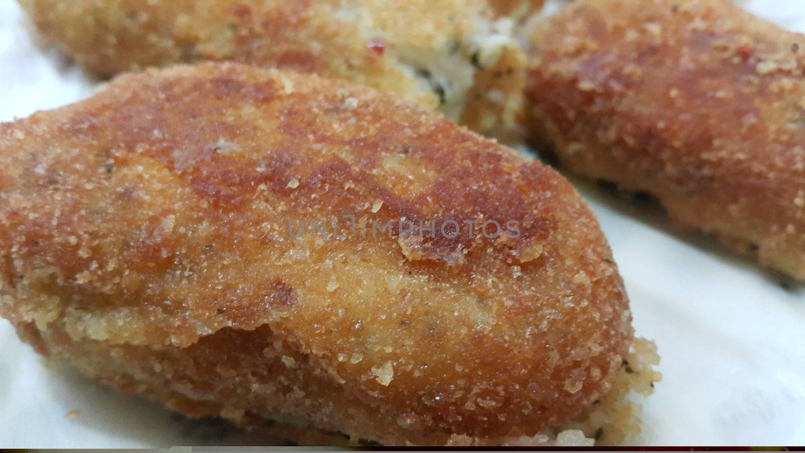 Closeup perspective view of home made spicy and delicious croquettes served in ceramic plate over wooden floor