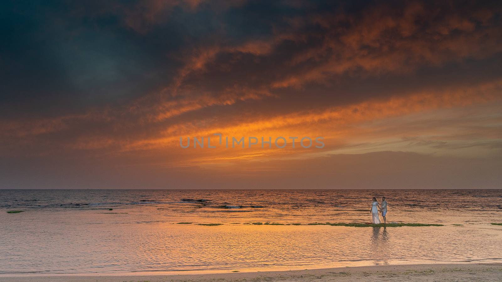 Colorful sunset with cliffs in the water on sea beach by javax