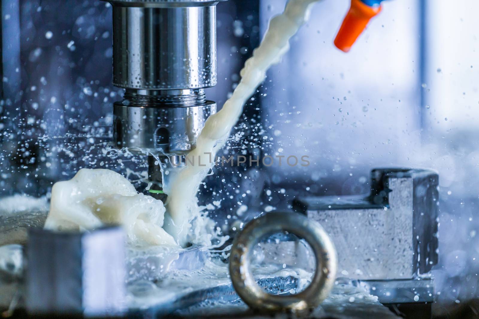 A process of vertical cnc steel milling with external water coolant streams and splashes. Fast shutter speed for motion freezing.