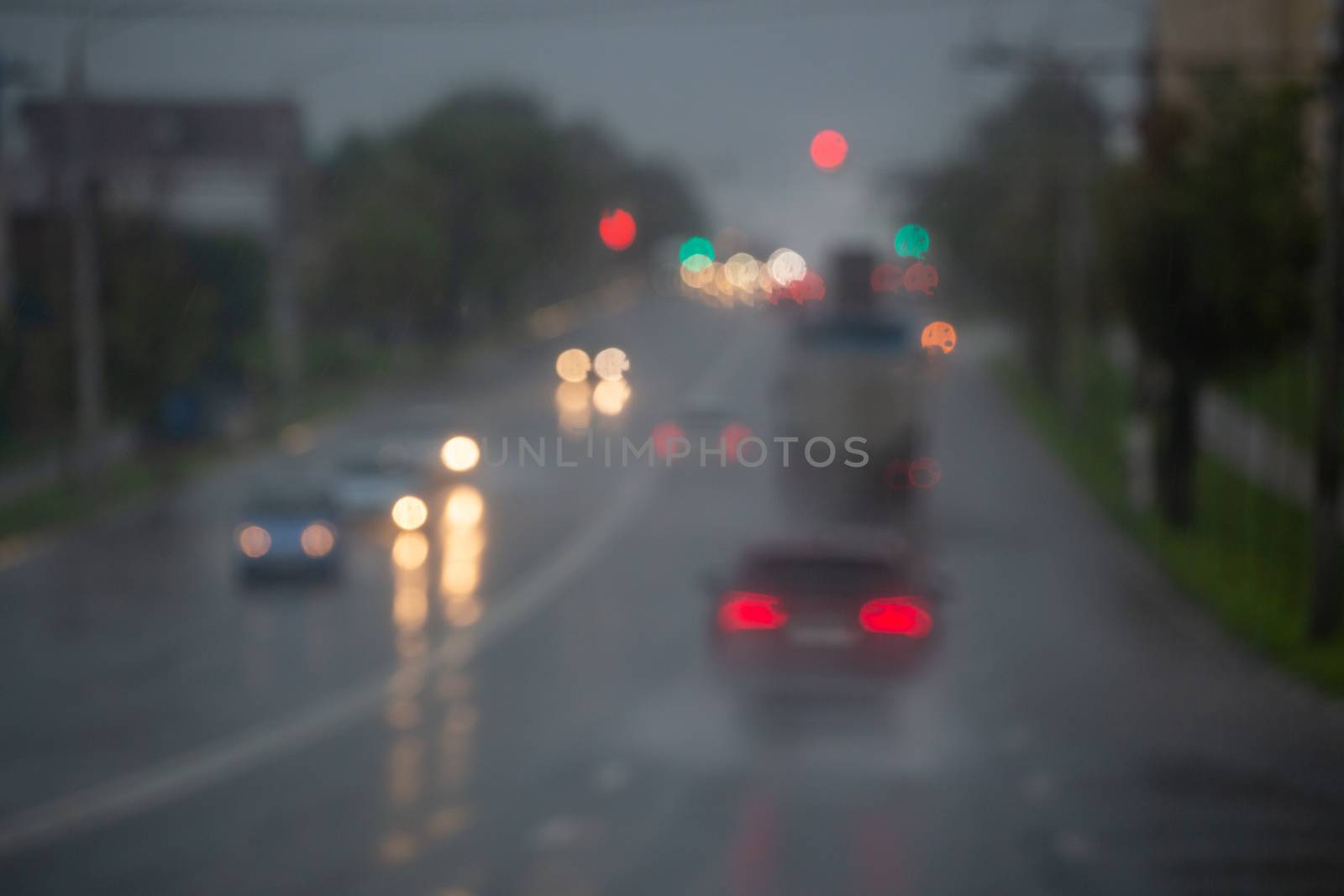 Defocused picture of evening city street car traffic after rain - view from road.