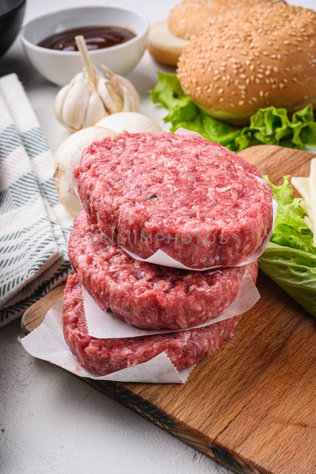 Raw ground beef meat cutlets for burger on white textured background.