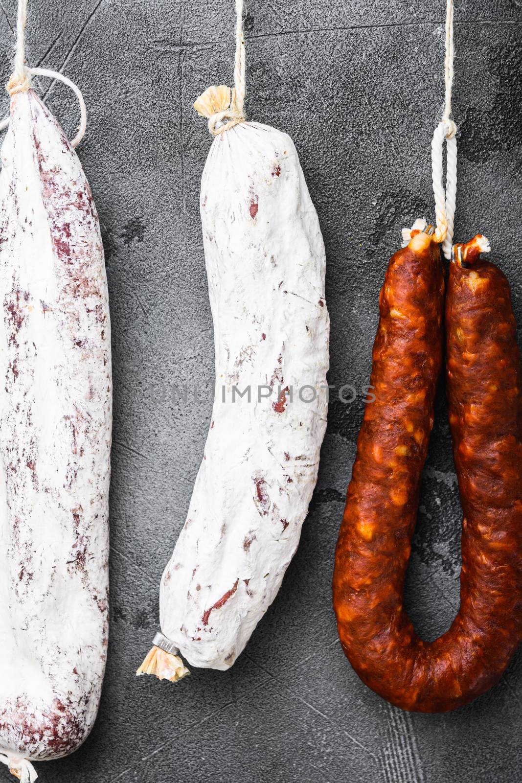 Spanish salami from a rack at market on grey textured background, flat lay.