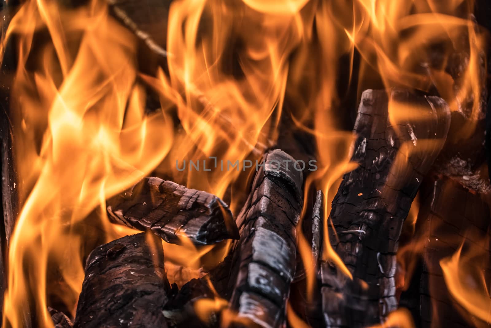 Photo Burning firewood and coals.Flaming burning sparks close-up, fire patterns.View of red hot glowing wood inside stove.Embers and fire in furnace or campfire.Abstract fire flame background