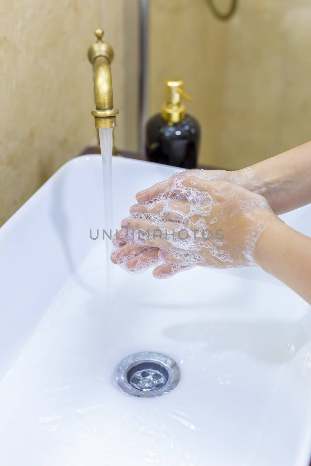 Woman washing and disinfecting hands with soap and hot water as part of coronavirus prevention and protection protocols; stop spreading covid-19 hygiene protocols. Focus on her finger.