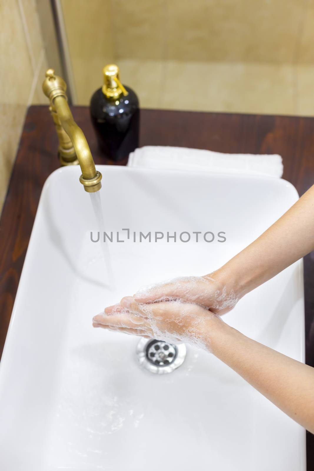 Woman washing and disinfecting hands with soap and hot water as part of coronavirus prevention and protection protocols; stop spreading covid-19 hygiene protocols