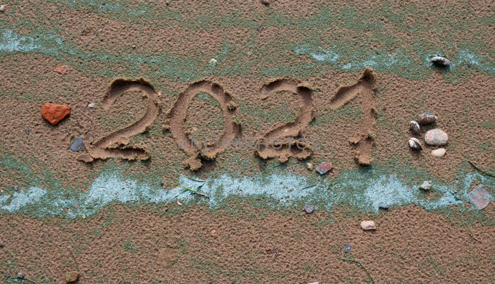 A small red stone - the heart and numbers of 2021 on the sand. Summer beach holidays . The message is handwritten.The concept of a New year by lapushka62