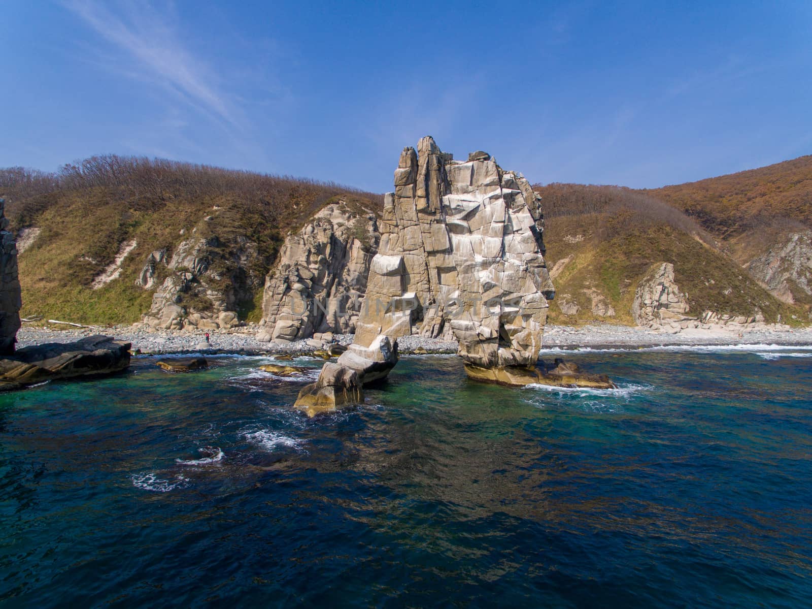 A huge stone in the form of an arch stands in the middle of the sea against the background of sheer cliffs. The territory of the Sikhote-Alin Biosphere Reserve in the Primorsky Territory by PrimDiscovery
