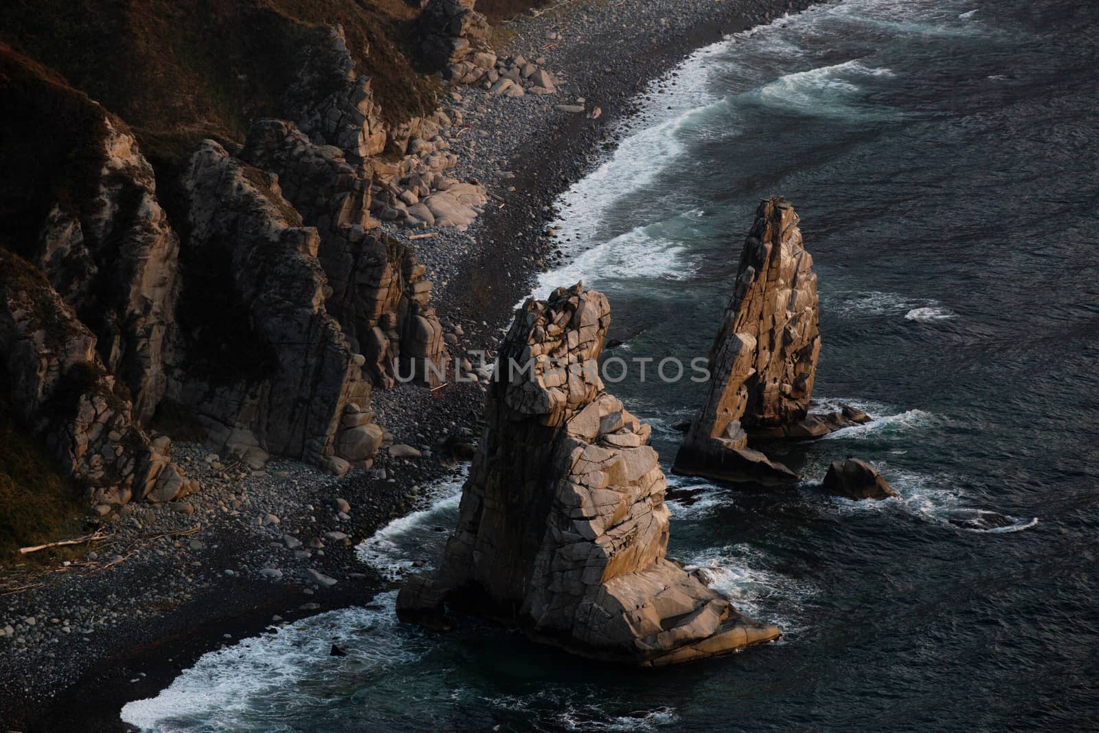 A huge stone in the form of an arch stands in the middle of the sea against the background of sheer cliffs. The territory of the Sikhote-Alin Biosphere Reserve in the Primorsky Territory by PrimDiscovery