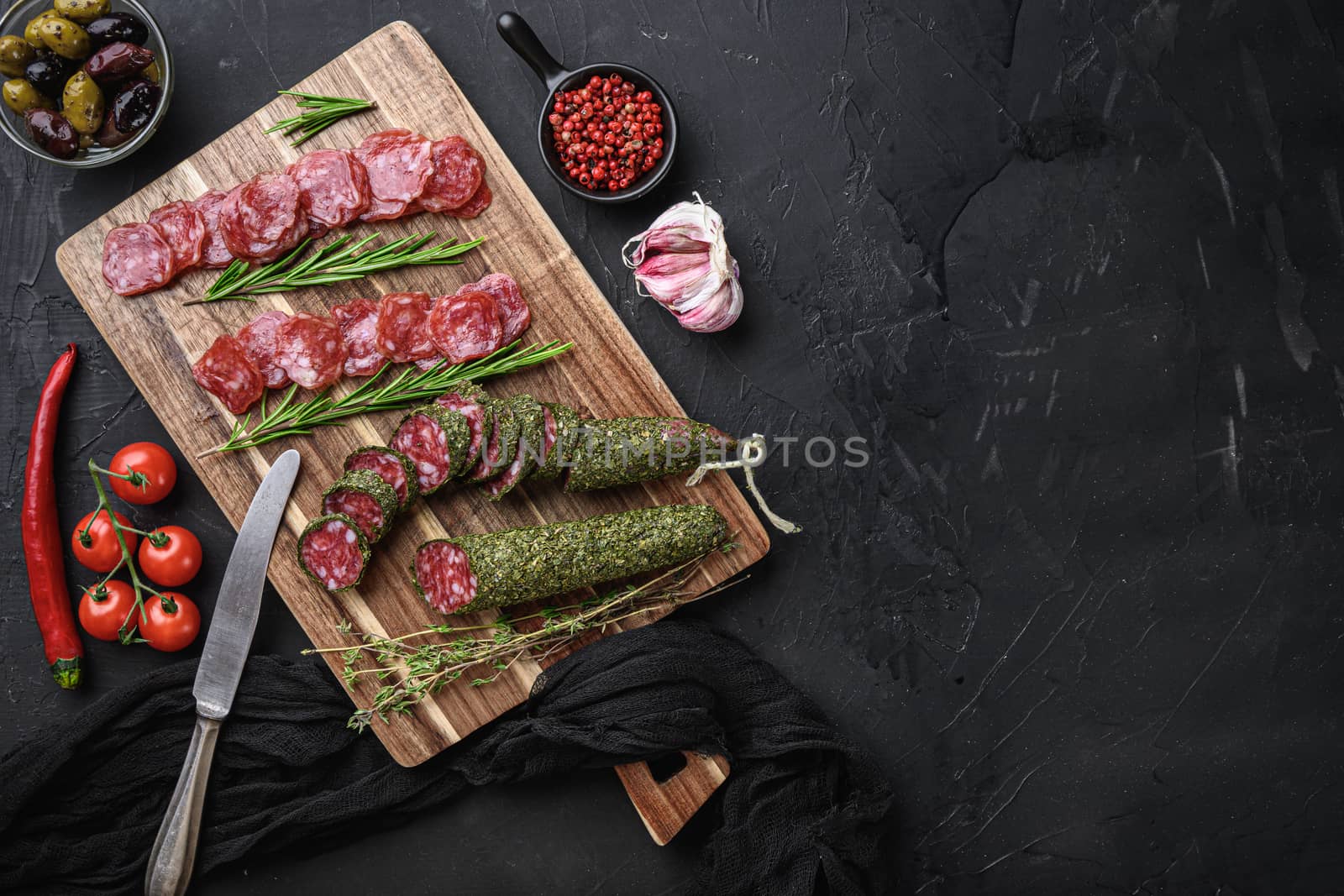 Spanish fuet salami sausage slices on black textured background with space for text.