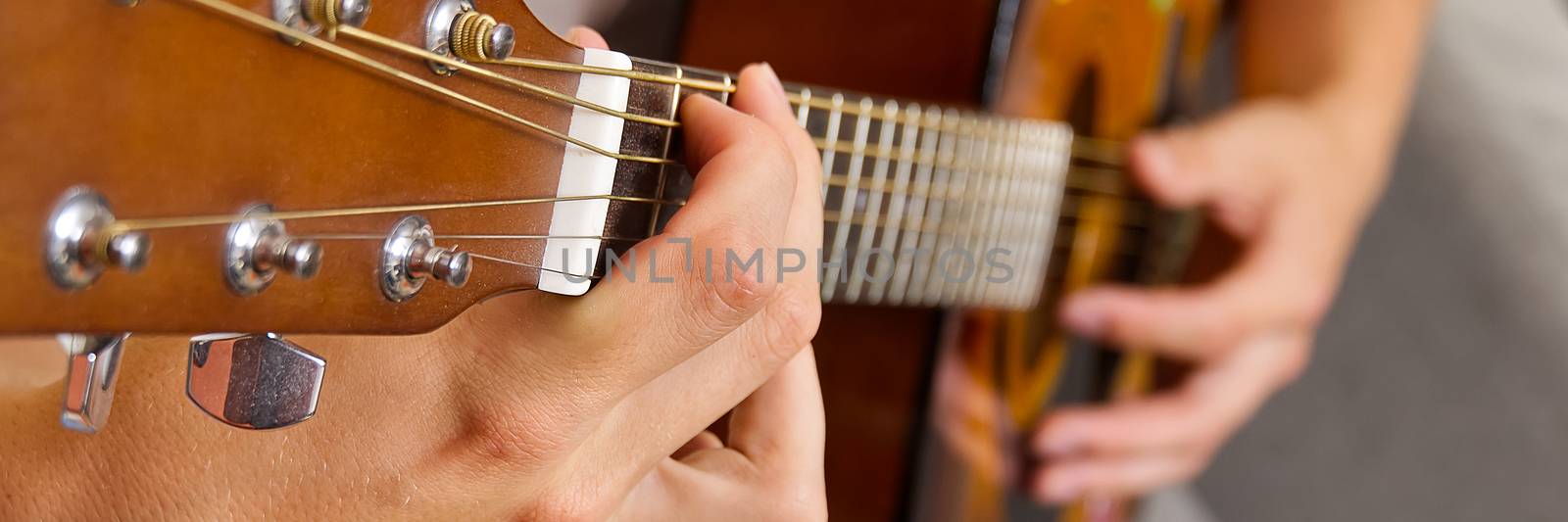 Young boy playing guitar. Close-up of man hand playing classic guitar. teenager learning playing guitar. Banner or panoramic shot. by PhotoTime