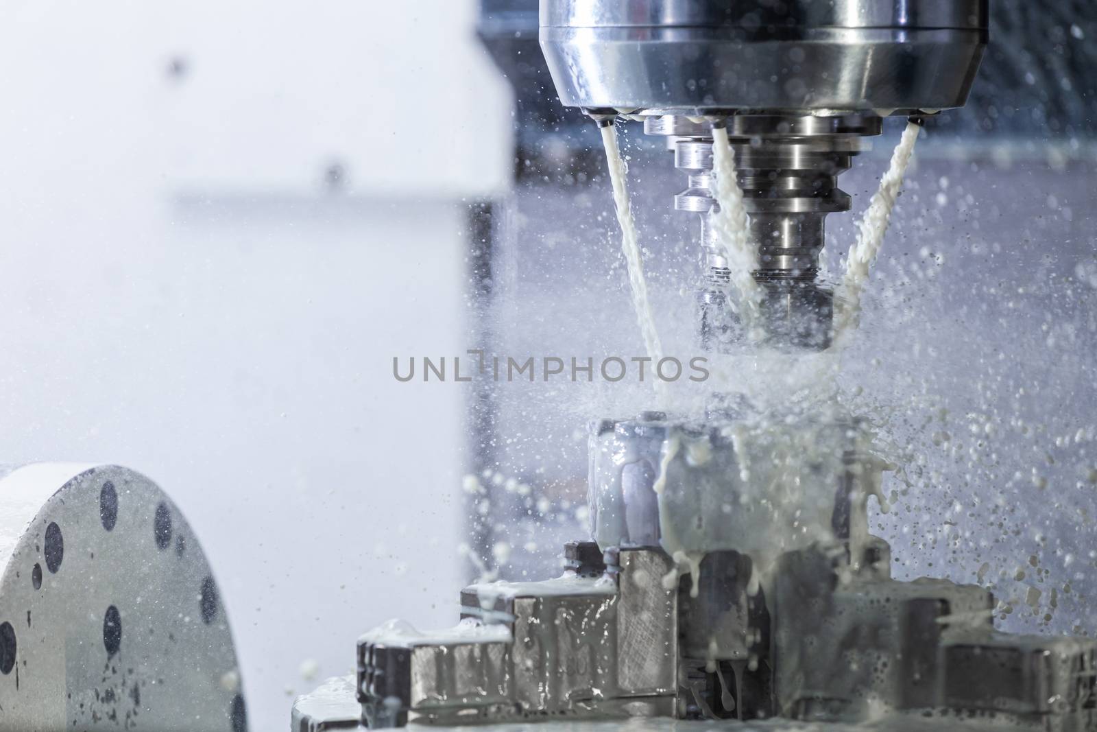 a process of industrial wet milling in 5-axis cnc machine with coolant flow under pressure and freezed streams and splashes.