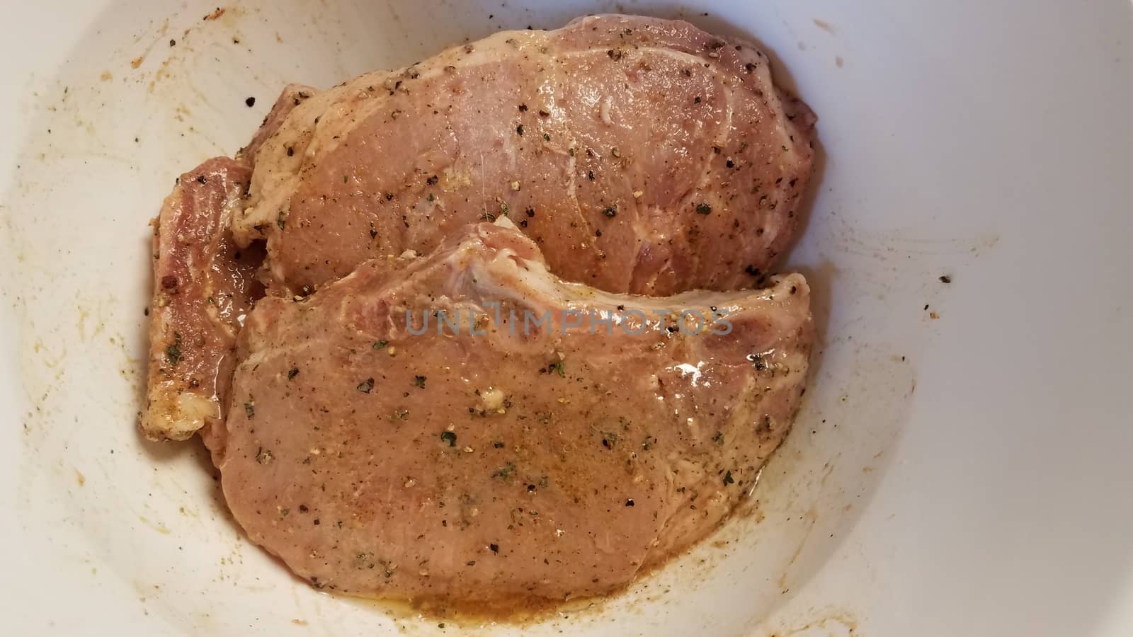 seasoned pork chops with oil in white container by stockphotofan1